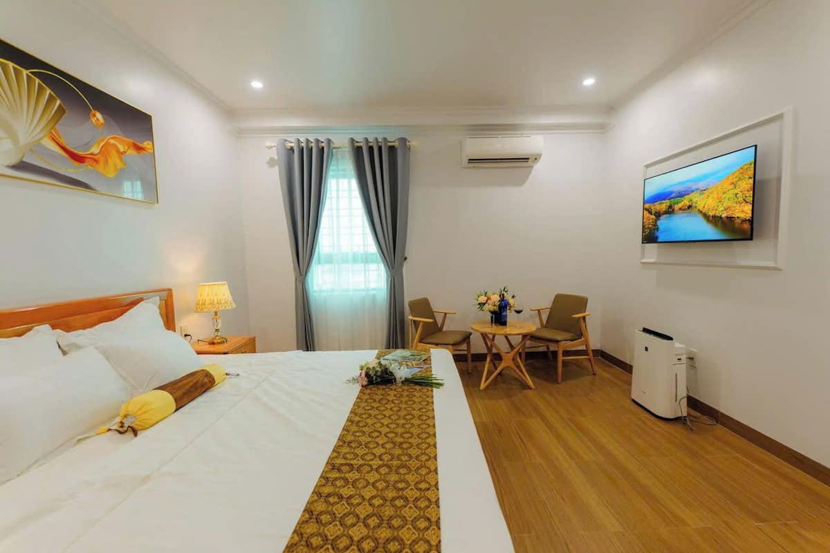 Een hotelkamer met een bed, bureau, stoel, televisie en airconditioning.