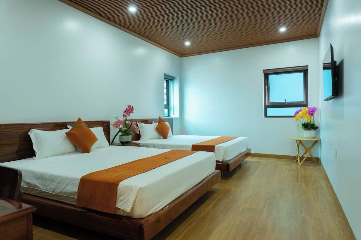 Een hotelkamer met twee bedden, een tafeltje, een televisie en een raam.