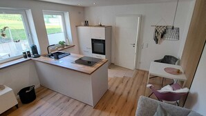 Cocina compacta con una isla central, horno empotrado y zona de comedor con una silla.