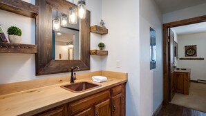 A bathroom with a wooden vanity, a large mirror, and a hanging light fixture. - NLTH3 | Mountain Living | Ski Out/Walk In | Winter Shuttle | Hot Tub (Steamboat Springs)