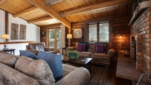 A rustic cabin interior with wooden beams, leather sofas, and a brick fireplace. - NLTH3 | Mountain Living | Ski Out/Walk In | Winter Shuttle | Hot Tub (Steamboat Springs)