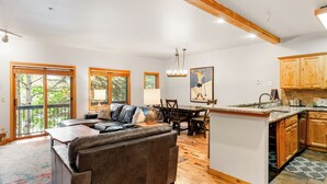 Uma sala ampla com um sofá grande, mesa de jantar de madeira e cozinha com armários de madeira.