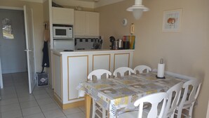 Una pequeña cocina con microondas, un lavamanos y una zona de comedor con mesa y sillas.