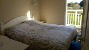 Un dormitorio con cama, mesitas de noche y ventana con vista a una terraza.