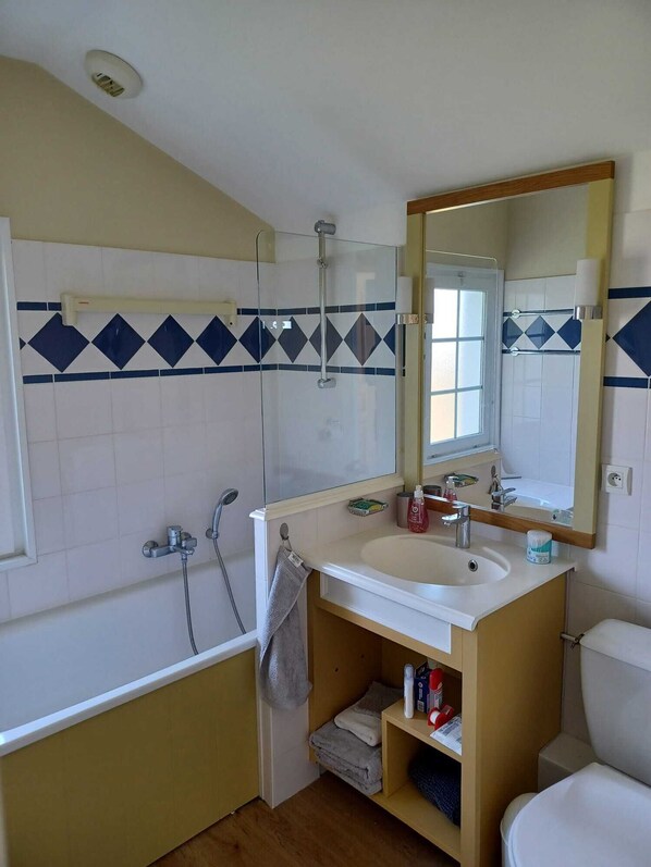 A bathroom with a bathtub, a sink, a mirror, and a toilet.