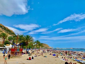 Ein überfüllter Strand mit Palmen und blauem Himmel.
