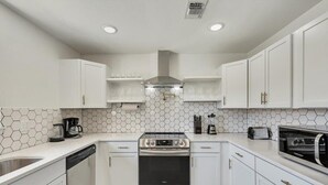 A modern kitchen with white cabinets, a stainless steel oven, and a hexagonal tile backsplash.