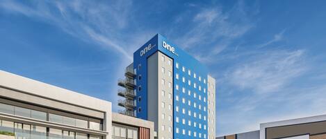 A modern hotel with a prominent blue and white facade, featuring a large number of windows and a flat roof.