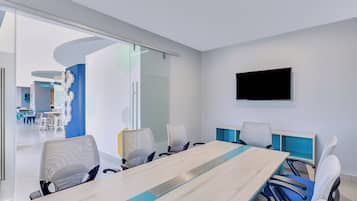 A modern conference room with a long table, six chairs, and a large screen on the wall.