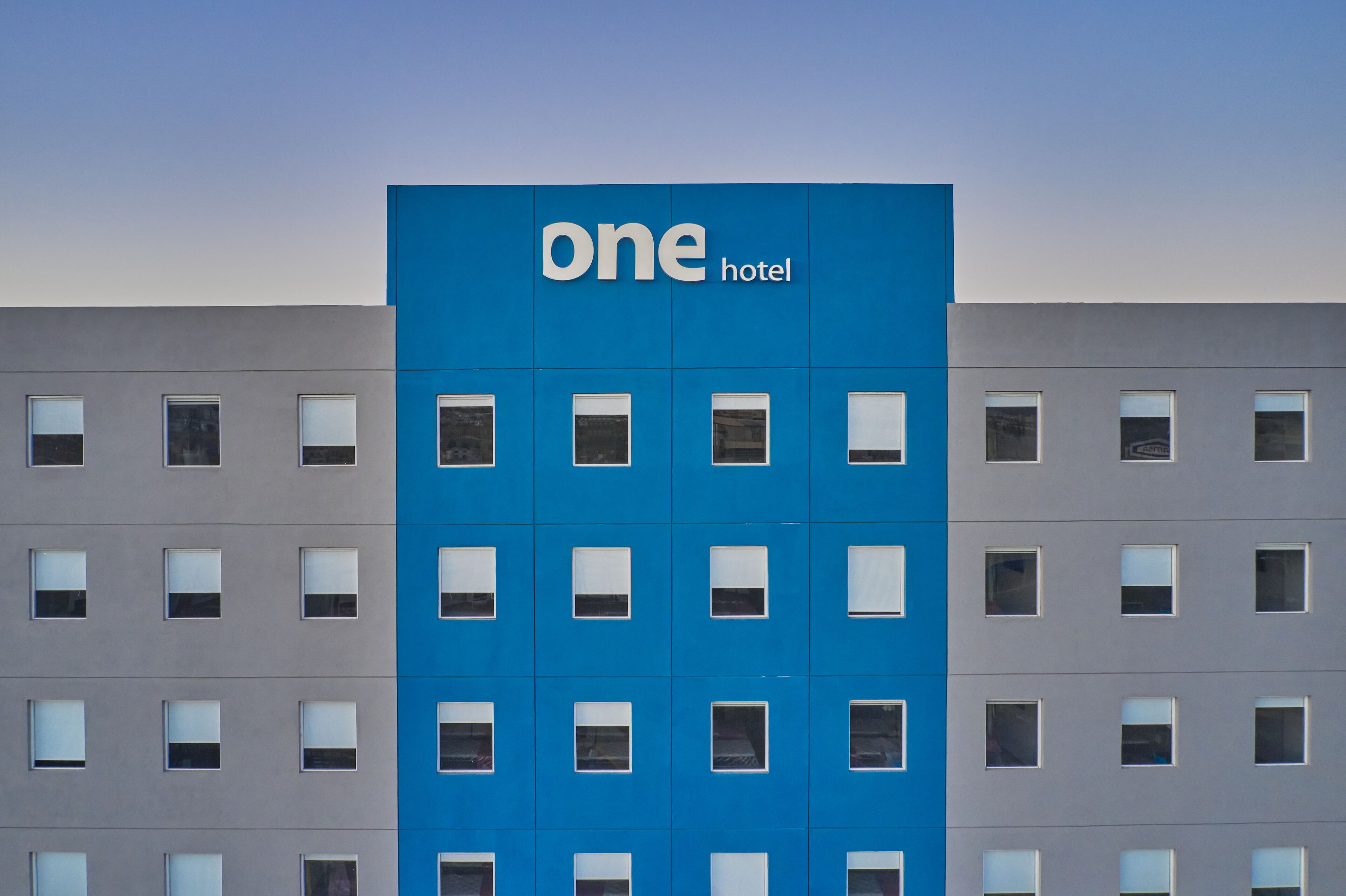 Ein Gebäude mit blauer Fassade und dem Schriftzug "one hotel" darauf.