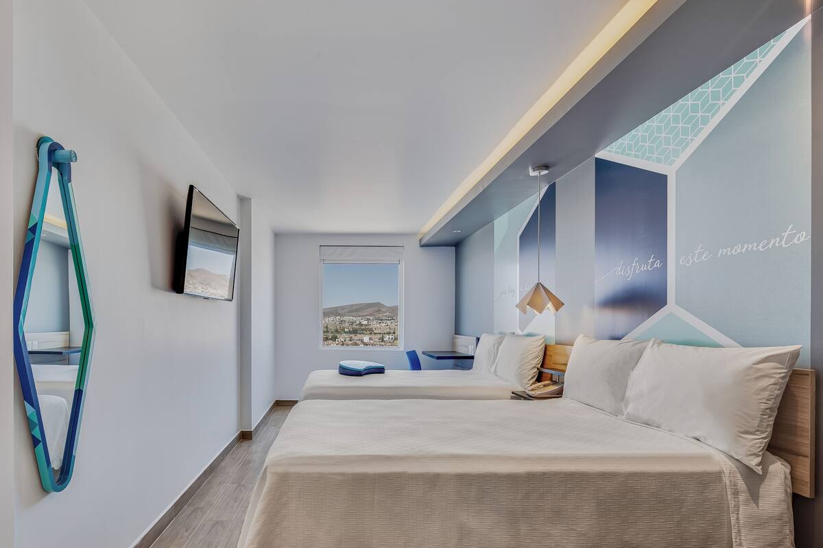 Una habitación de hotel moderna con una cama grande, un escritorio y vistas a la ciudad.