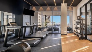 Une salle de sport moderne équipée de tapis de course, de ballons d’exercice et d’un support pour haltères.