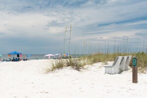 Ein Strand mit weißem Sand, Liegestühlen, Sonnenschirmen und einem Schild mit der Aufschrift '73 ST'.