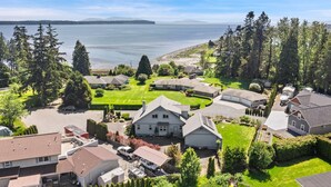 A residential area with houses, a large lawn, and a view of a body of water. - Seashell Cottage w/ Ocean Views, Hot Tub & Game Room: Ideal for Family & Pets (Blaine)