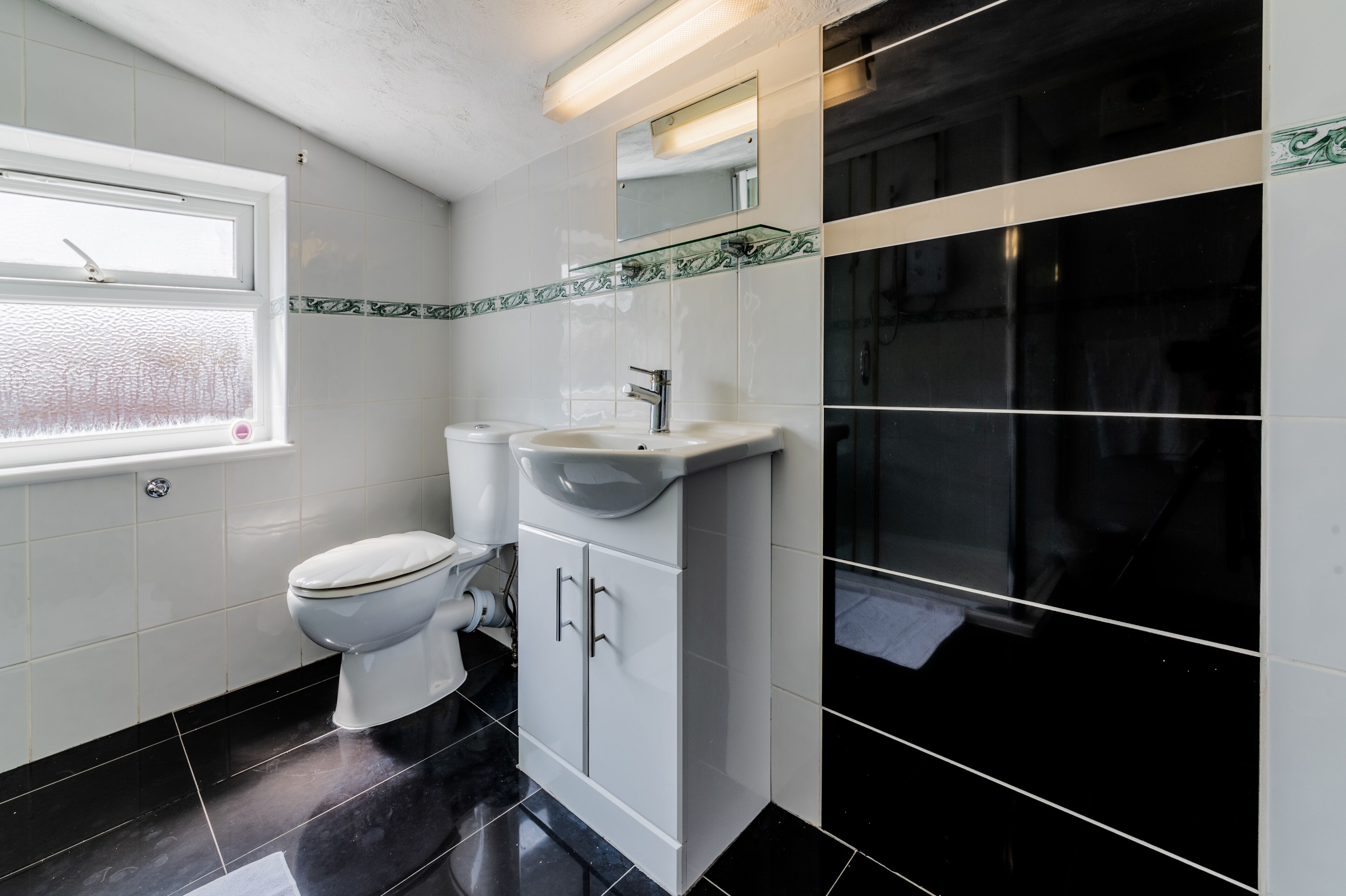 A bathroom with a toilet, sink, and mirror.