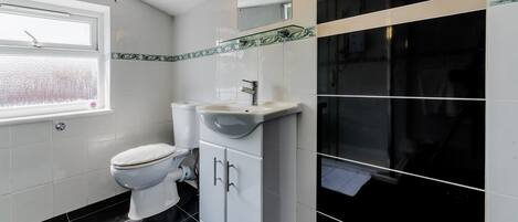 A bathroom with a toilet, sink, and mirror.