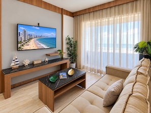 A modern living room with a large flat-screen TV, a sofa, a coffee table, and a potted plant.