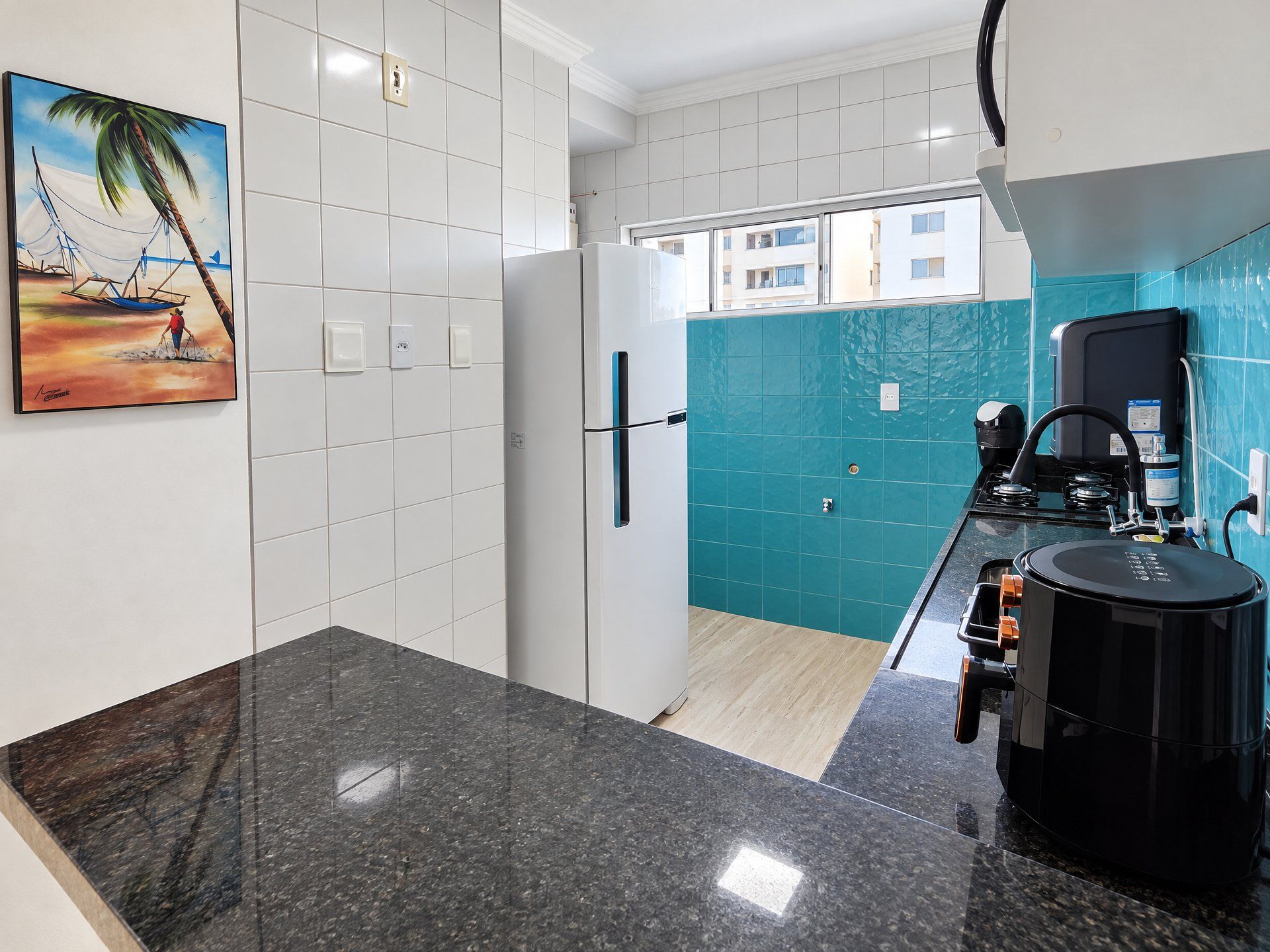 Una cocina moderna con encimera de granito, cafetera y vistas al exterior.