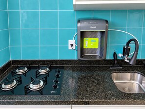 Una cucina con piano cottura a gas, dispenser di acqua e lavandino.