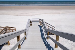 A wooden boardwalk leading to a beach with a clear view of the ocean. - Paradisea (St. Augustine)