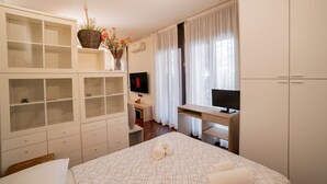 Une chambre à coucher avec un lit, un bureau, une télévision et une armoire.