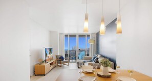 A modern living room with a dining area, large windows, and a view of the city.