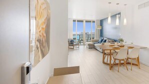 A modern living room with a dining area, large windows, and a view of the city. - Upper Apartment: Pool + Gym + Amazing view (Hallandale Beach)