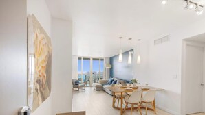 Een moderne woonkamer met een eethoek, grote ramen en uitzicht op de stad.