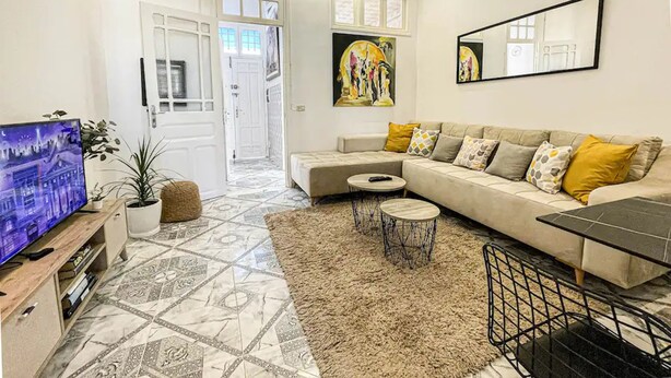 A living room with a sofa, a coffee table, a TV, and a potted plant. - Cosy Apartment in La Marsa Corniche (Site archéologique de Carthage)