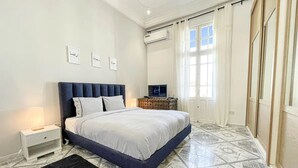 A bedroom with a bed, nightstands, a TV, and a window with curtains. - Cosy Apartment in La Marsa Corniche (Site archéologique de Carthage)