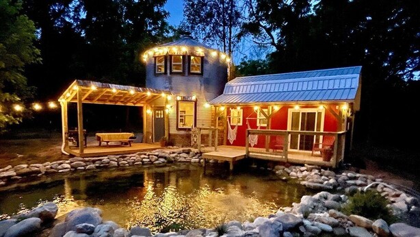 A house with a pond, wooden deck, and stone border.