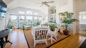 A spacious living room with a high ceiling, large windows, and a view of the city.