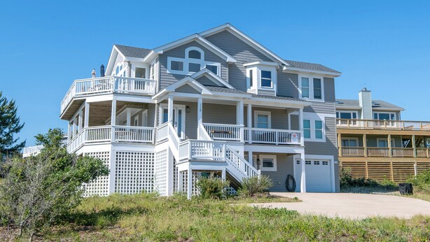 A multi-story house with a balcony, a garage, and a driveway.