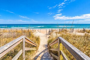 A wooden pathway leading to a beach with a clear view of the ocean.