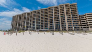 A multi-story hotel with a flat roof and numerous balconies, located adjacent to a sandy beach. - Perfect location at Phoenix X next door to FloraBama (Orange Beach)