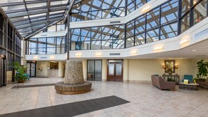 A spacious lobby with a high ceiling, glass panels, a central decorative column, and a reception desk. - Perfect location at Phoenix X next door to FloraBama (Orange Beach)