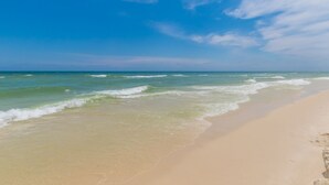 A beach with clear skies and gentle waves. - Perfect location at Phoenix X next door to FloraBama (Orange Beach)