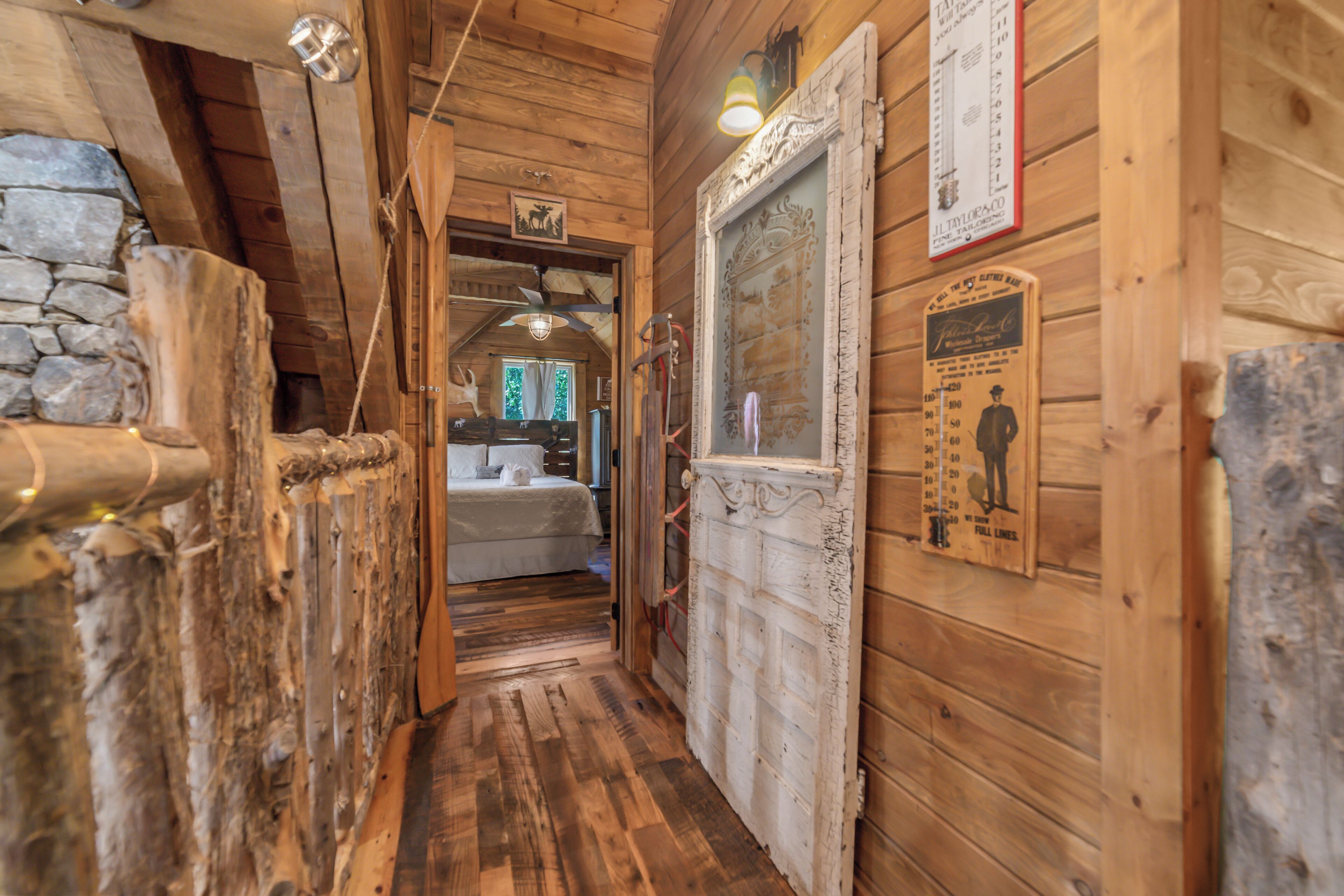 Ein Holzboden mit einer Steinsäule an einer Seite, einem Bett im Hintergrund und einer Tür mit einer Größenangabe an der Wand.