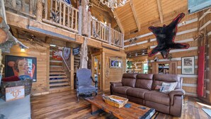 Un interior rústico con una escalera de madera, un sofá de cuero y una cabeza de animal montada.