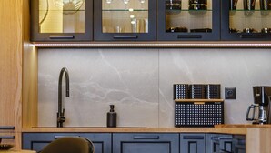 A modern kitchen with dark cabinetry, a marble backsplash, and a built-in coffee station. - Apartament CHICAGO (Nowy Targ)