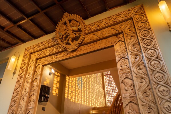Una puerta de madera tallada con intrincados diseños tradicionales y un techo con estructura de vigas de madera.