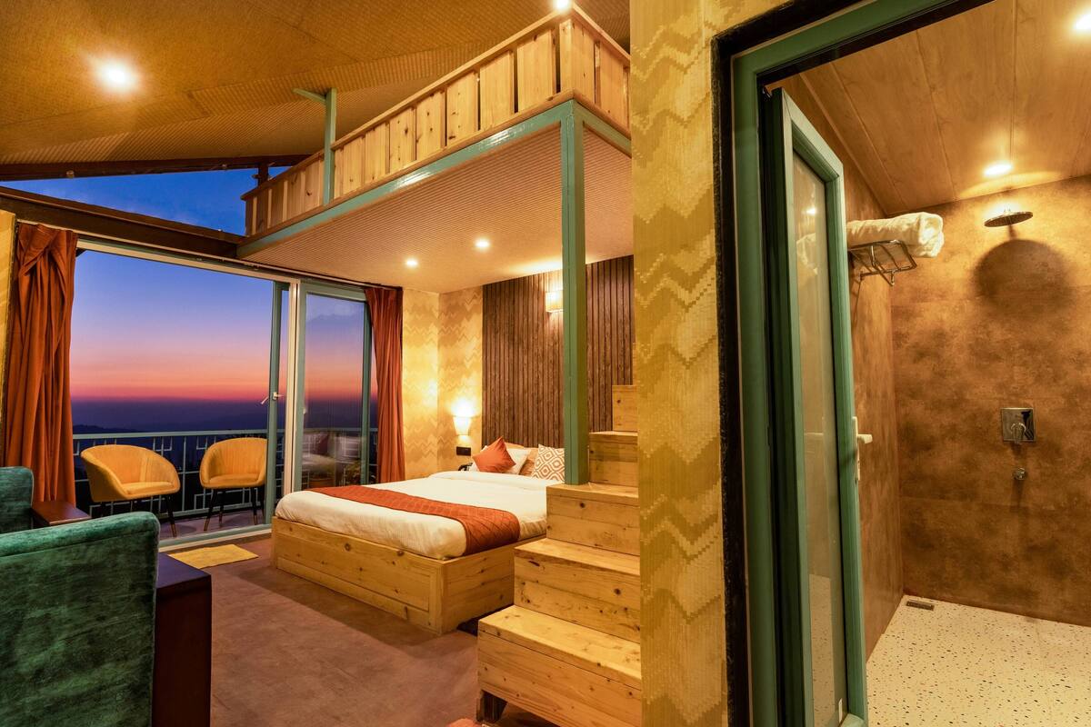 Une chambre spacieuse avec un grand lit, des meubles en bois, un balcon avec vue et un espace douche.