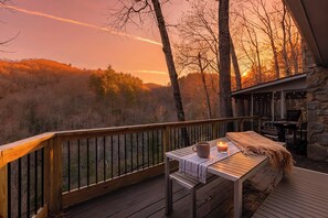 A wooden deck with a table, a candle, and a bench. - Laurel Creek Cottage | Pets | VIEW | Screen Porch (Watauga County)