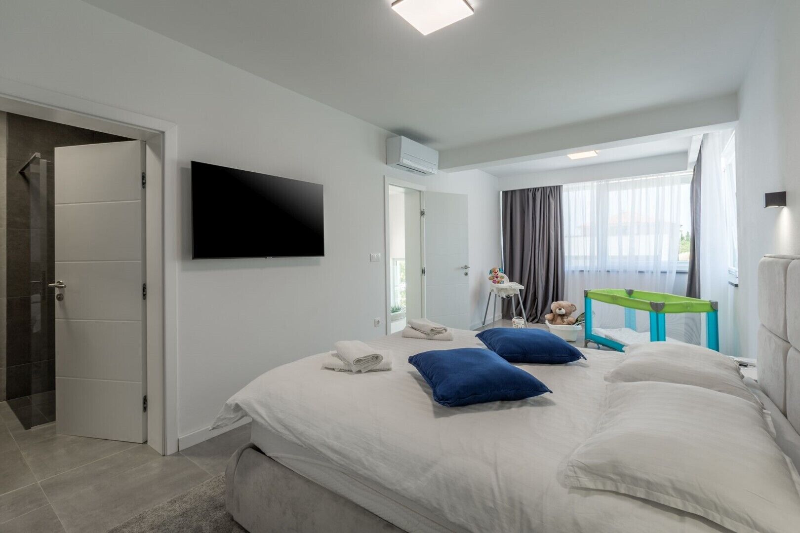 Een moderne hotelkamer met een groot bed, een flatscreen televisie, een balkon met uitzicht en een klein tafeltje met een stoel.