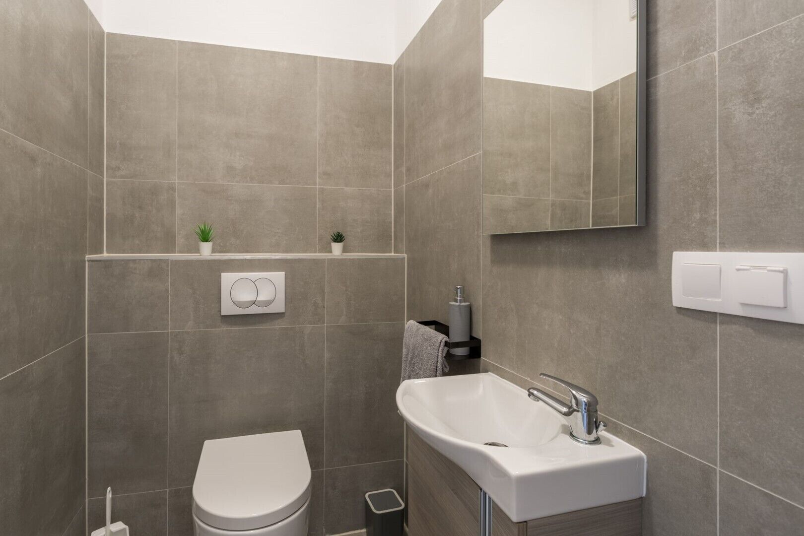 A modern bathroom with a toilet, sink, and mirror.