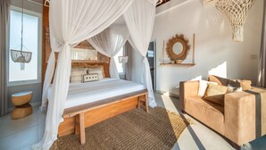 A bedroom with a four-poster bed, a sofa, a woven rug, and a hanging light fixture. - Villa Moana Canggu by Villa Finder (Canggu)