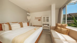 Une chambre d’hôtel avec un grand lit, un canapé, une armoire et une vue sur la verdure.