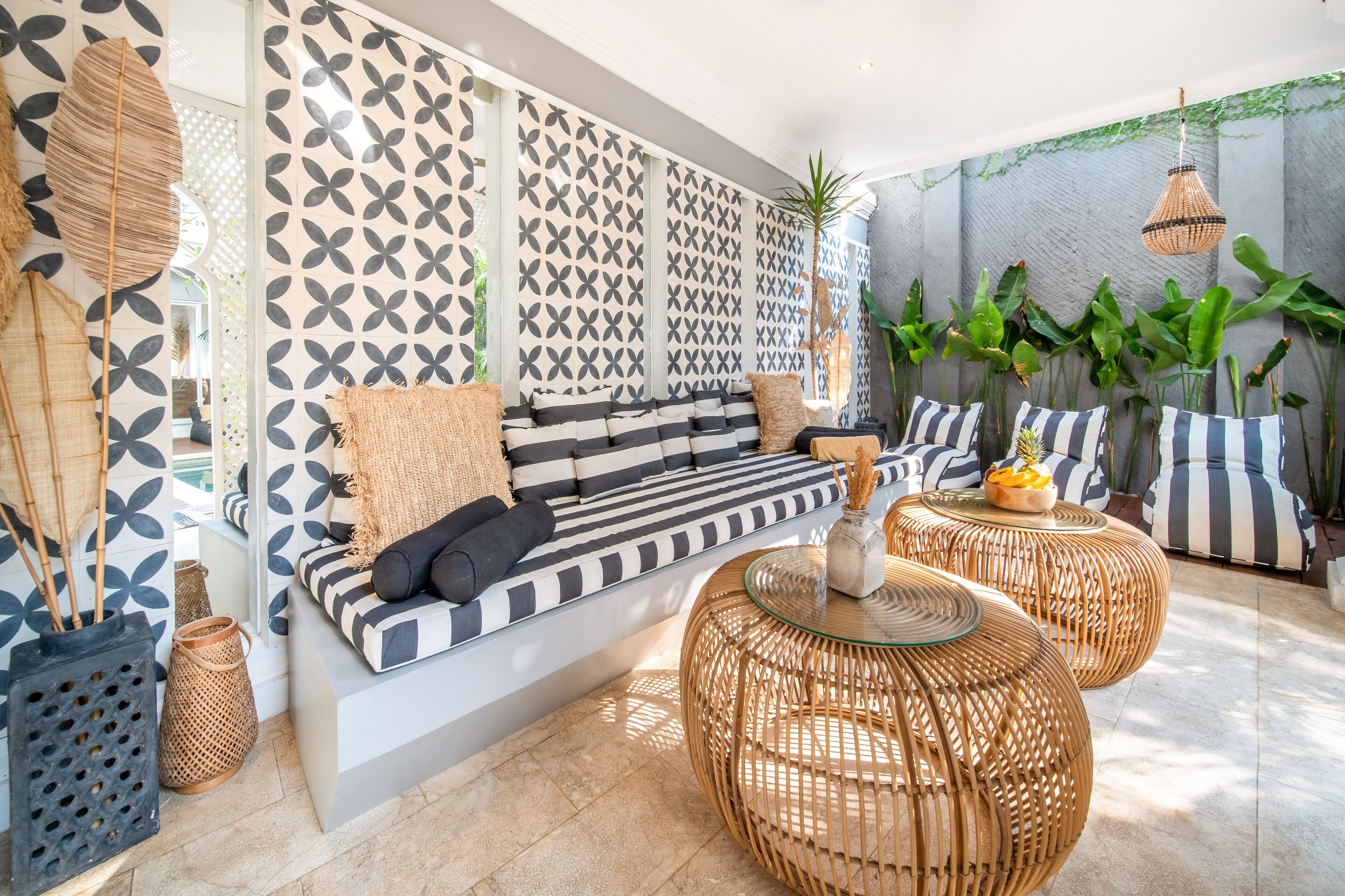 A modern living room with a patterned wall, a sofa with striped cushions, and wicker coffee tables.