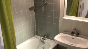 Een badkamer met een bad, douche en wastafel.