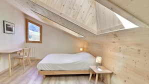 A bedroom with a sloped ceiling, a bed, a desk, and a chair. - 10m from ski slopes, 4th floor, 62m², Méribel-Mottaret (Méribel - Les Allues)